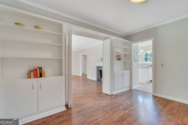 interior space featuring built in shelves, light wood-type flooring, and crown molding