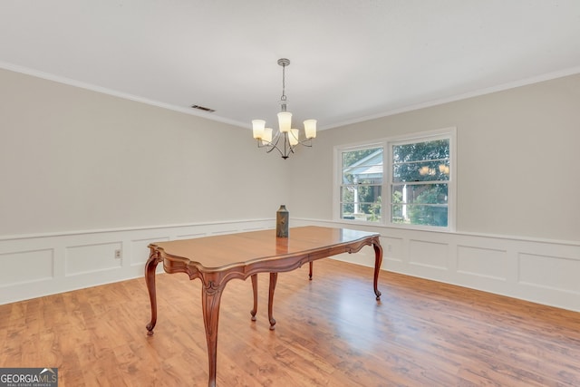 dining area with light hardwood / wood-style flooring, ornamental molding, and a notable chandelier