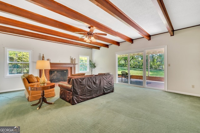 carpeted living room featuring beam ceiling, a fireplace, and ceiling fan