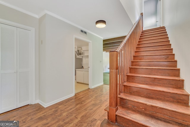 stairway with crown molding and wood-type flooring