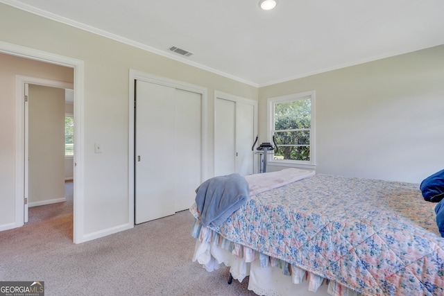 bedroom with multiple closets, ornamental molding, and light colored carpet