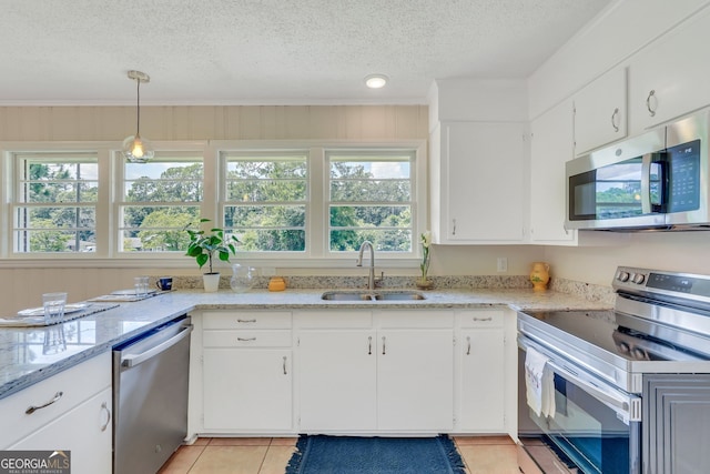 kitchen with a textured ceiling, appliances with stainless steel finishes, white cabinets, light tile patterned floors, and sink