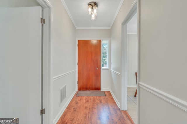 doorway with crown molding and light hardwood / wood-style floors