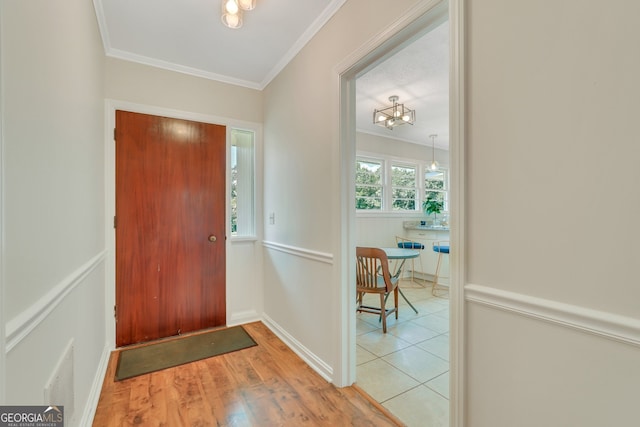 foyer with light hardwood / wood-style flooring, a notable chandelier, and crown molding