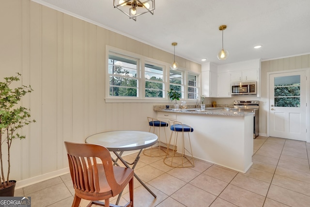 kitchen featuring crown molding, light tile patterned floors, white cabinets, light stone countertops, and kitchen peninsula