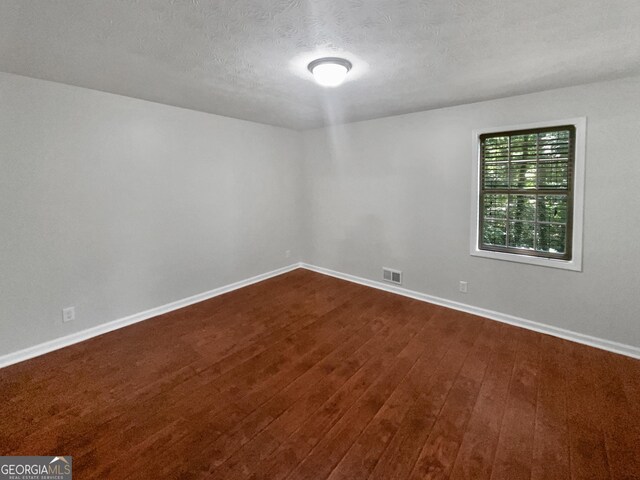 unfurnished room with a textured ceiling and wood-type flooring