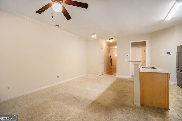 unfurnished living room with baseboards, light colored carpet, a sink, and ornamental molding