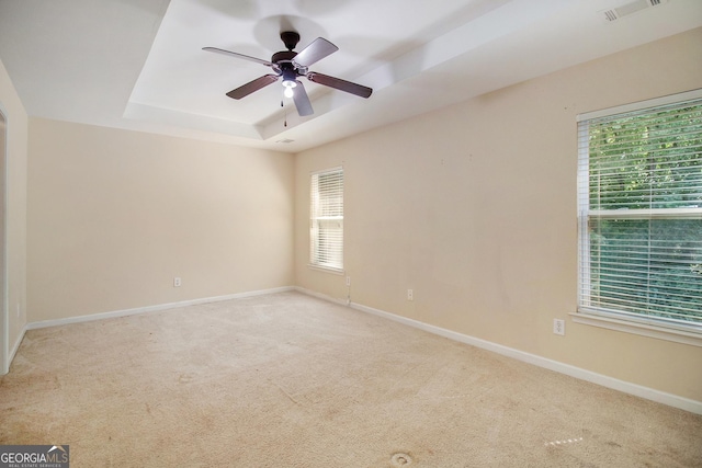 empty room featuring baseboards, a tray ceiling, visible vents, and light colored carpet