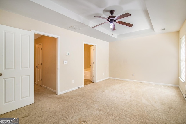 unfurnished bedroom featuring baseboards, a tray ceiling, visible vents, and light colored carpet