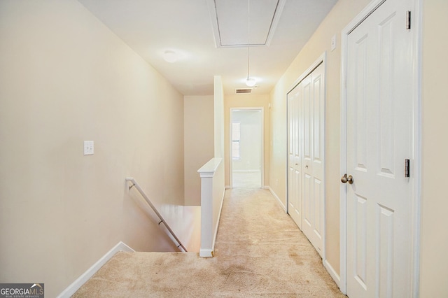 corridor with light carpet, visible vents, baseboards, an upstairs landing, and attic access