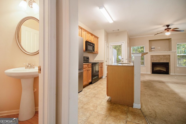 kitchen with a fireplace, open floor plan, light carpet, a sink, and black appliances