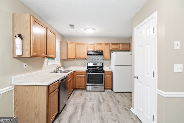 kitchen with sink, stainless steel appliances, light hardwood / wood-style flooring, and decorative backsplash