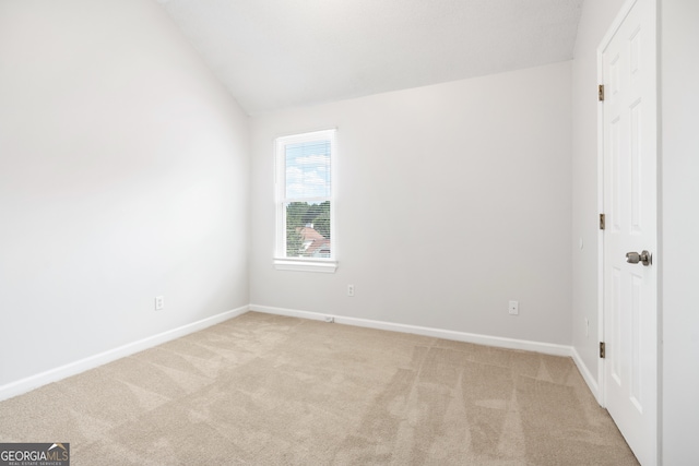 carpeted spare room with lofted ceiling