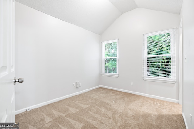 carpeted empty room featuring vaulted ceiling