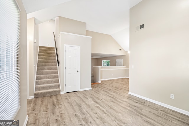 unfurnished living room with light wood-type flooring and high vaulted ceiling