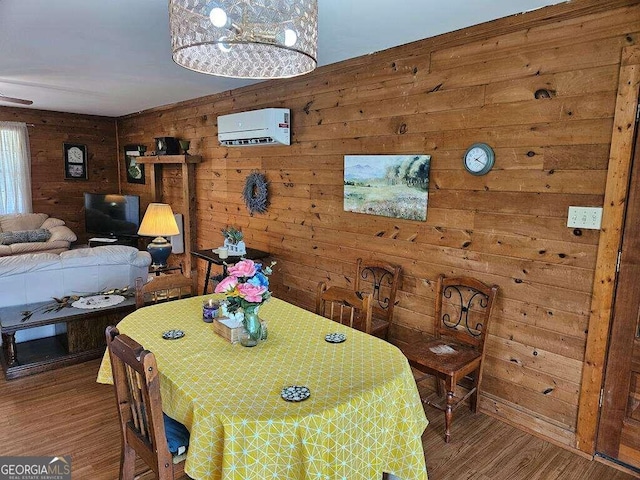 dining room with wood-type flooring, a wall unit AC, and wood walls