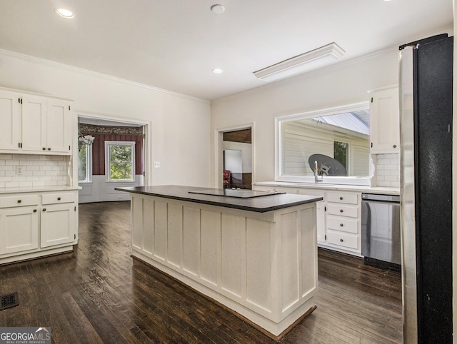 kitchen with a center island, backsplash, dark wood-type flooring, white cabinetry, and stainless steel appliances