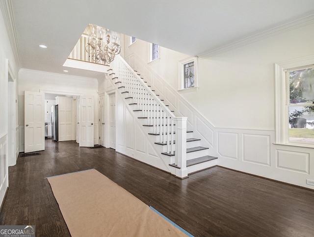 foyer entrance with dark hardwood / wood-style floors, ornamental molding, and a chandelier