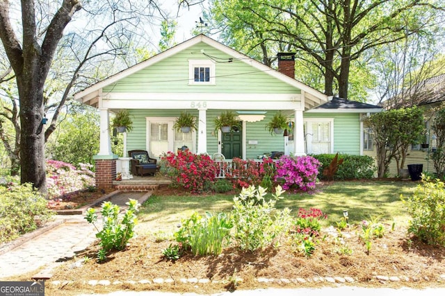 bungalow featuring covered porch and a front lawn