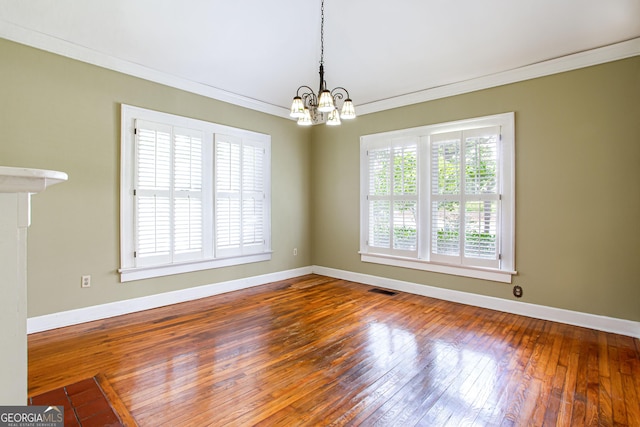 unfurnished room featuring a chandelier, crown molding, and hardwood / wood-style floors