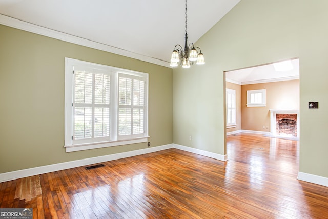 spare room with crown molding, lofted ceiling, wood-type flooring, and a notable chandelier