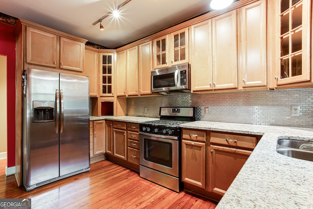 kitchen featuring light stone countertops, backsplash, appliances with stainless steel finishes, and track lighting