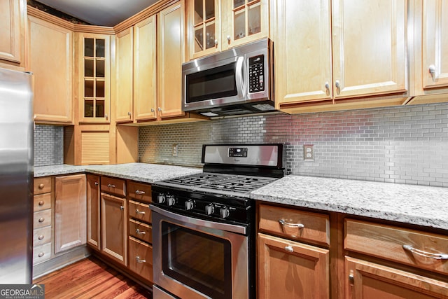 kitchen featuring light stone countertops, backsplash, and appliances with stainless steel finishes