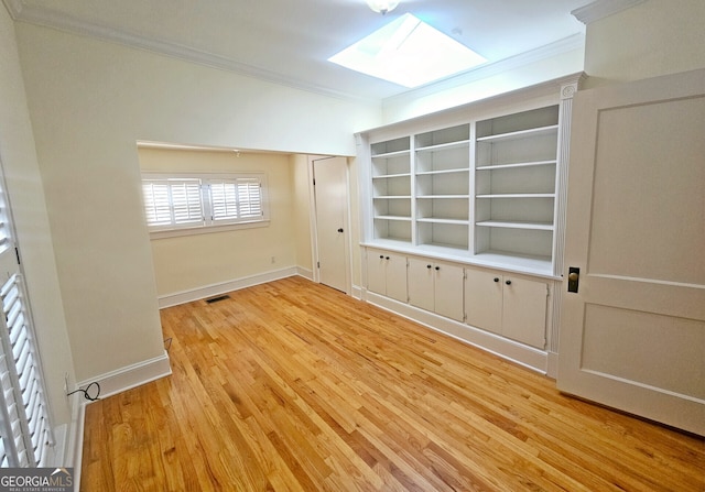 empty room with a skylight, ornamental molding, and wood-type flooring