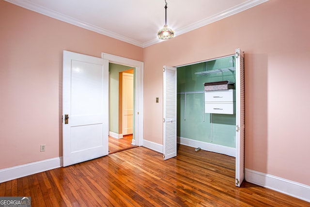 unfurnished bedroom featuring a closet, ornamental molding, and hardwood / wood-style flooring