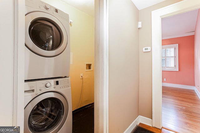 laundry room featuring stacked washer / dryer and hardwood / wood-style flooring