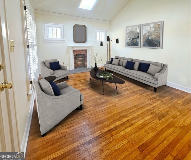 living room with vaulted ceiling with skylight, a brick fireplace, a wealth of natural light, and hardwood / wood-style floors