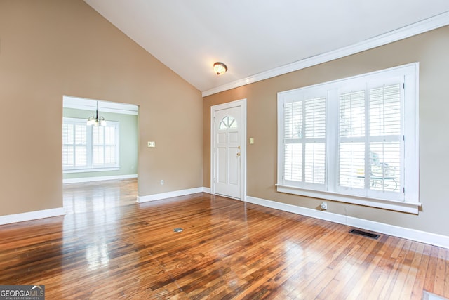 foyer entrance featuring high vaulted ceiling, crown molding, an inviting chandelier, and hardwood / wood-style floors