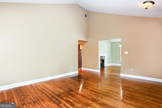 unfurnished living room with wood-type flooring and a towering ceiling