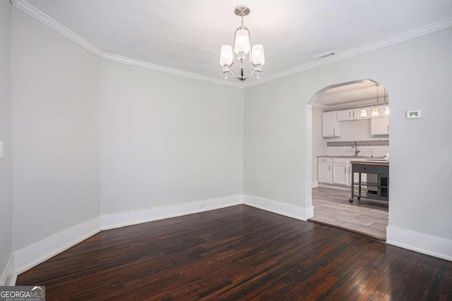 empty room featuring a notable chandelier, sink, wood-type flooring, and ornamental molding