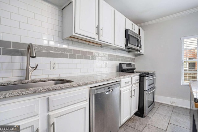 kitchen with stainless steel appliances, backsplash, light stone countertops, white cabinetry, and sink