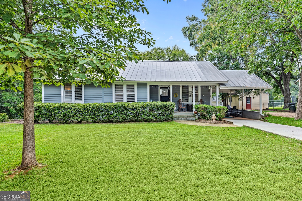 ranch-style house featuring covered porch and a front lawn