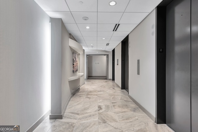 corridor featuring light tile patterned flooring, a paneled ceiling, and elevator