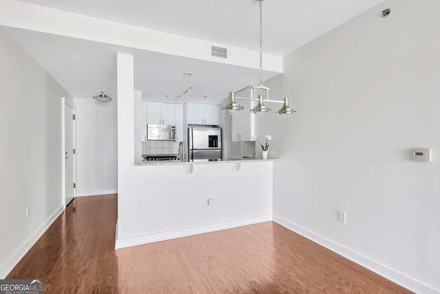 unfurnished living room with a notable chandelier, sink, and hardwood / wood-style floors