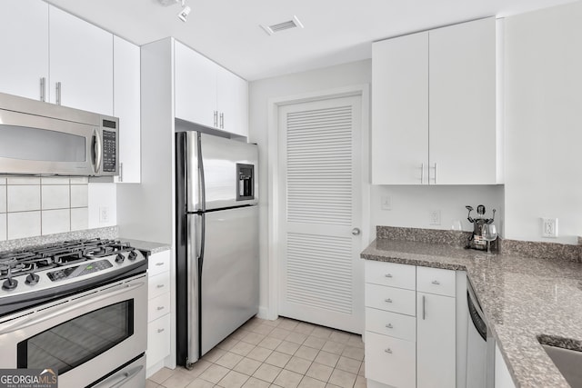 kitchen featuring light tile patterned floors, backsplash, white cabinets, and stainless steel appliances