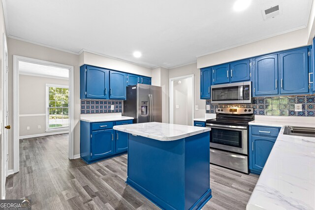 kitchen with backsplash, stainless steel appliances, blue cabinetry, and hardwood / wood-style flooring