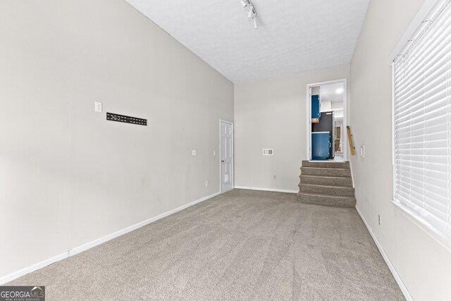 unfurnished room with carpet floors, track lighting, and a textured ceiling