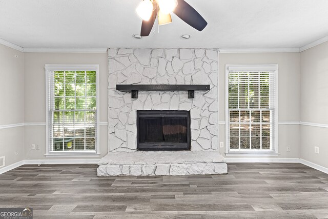 unfurnished living room with hardwood / wood-style floors, ornamental molding, ceiling fan, and a fireplace