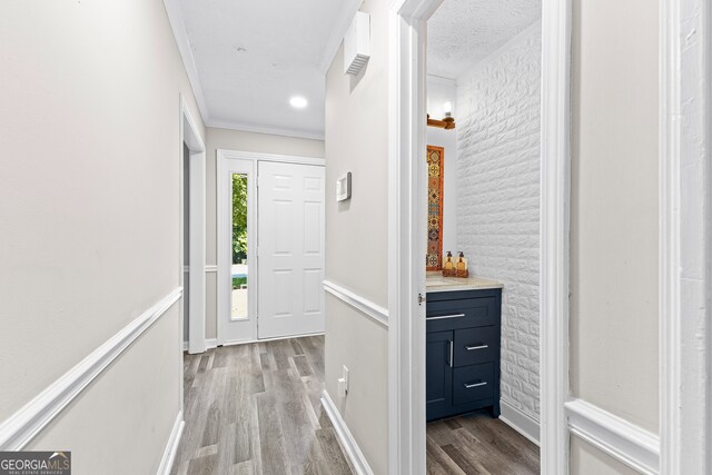 hall featuring a textured ceiling, light hardwood / wood-style floors, and ornamental molding