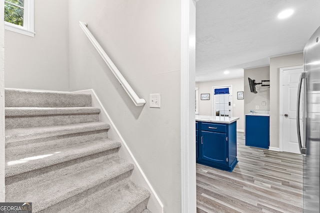 stairway featuring crown molding and hardwood / wood-style floors