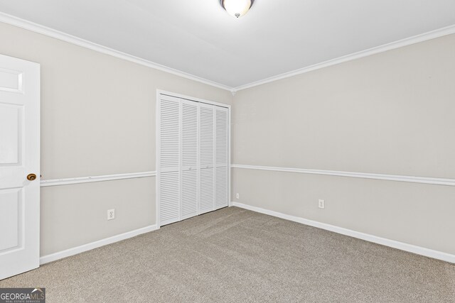 unfurnished bedroom with carpet, crown molding, and a closet