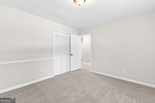 unfurnished bedroom with a closet and light colored carpet