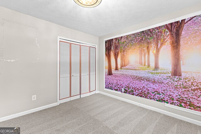 unfurnished bedroom featuring carpet, a closet, and a textured ceiling