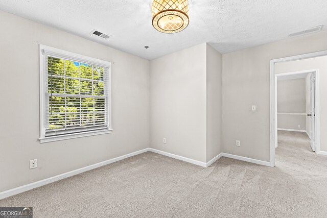 carpeted empty room with a textured ceiling