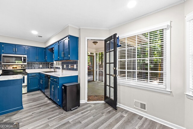 kitchen with stainless steel appliances, a healthy amount of sunlight, blue cabinets, and light hardwood / wood-style flooring