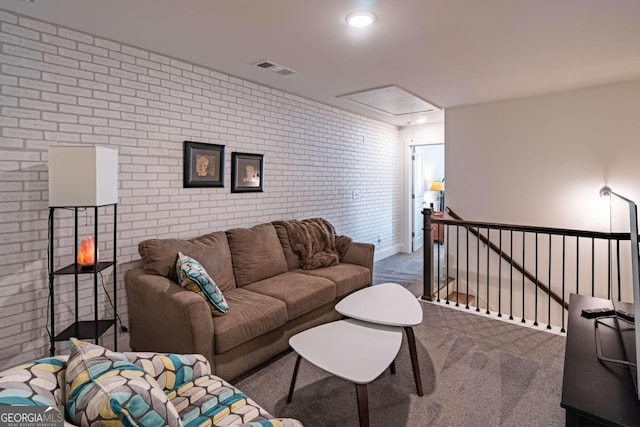 carpeted living room featuring brick wall